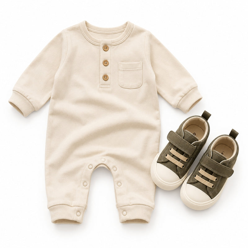 Beige baby onesie and green baby shoes on a white background