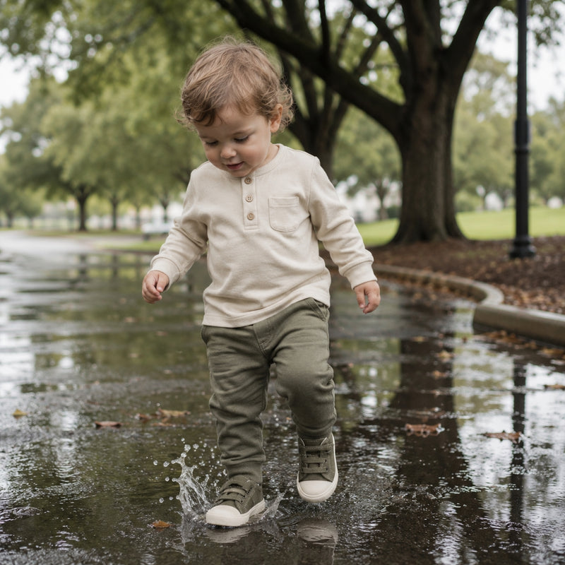 Child playing in a puddle in a park